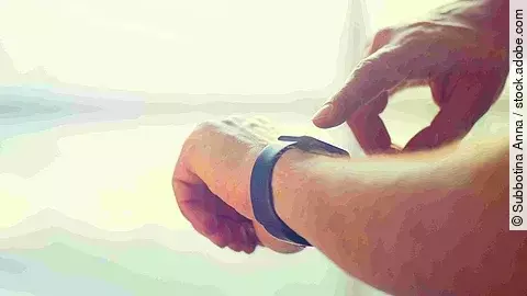 Zeiterfassung Eine Person tippt auf seine Smartwatch, die er am Handgelenk trägt.