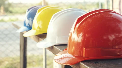 Baustelle Vier Bauarbeiterhelme liegen nebeneinander auf einem Geländer.