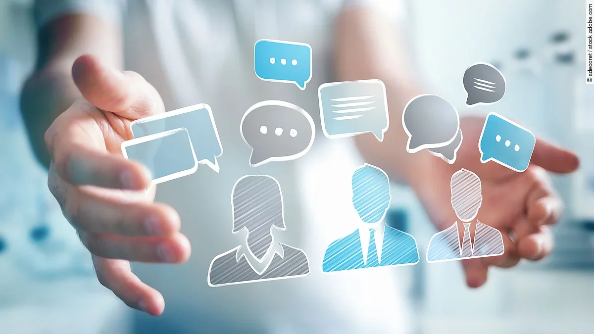 Person mit ausgestreckten Händen. Dazwischen eine holografische Anordnung von Chat-Symbolen.