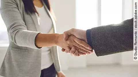 Handschlag einer Frau und eines Mannes im Anzug