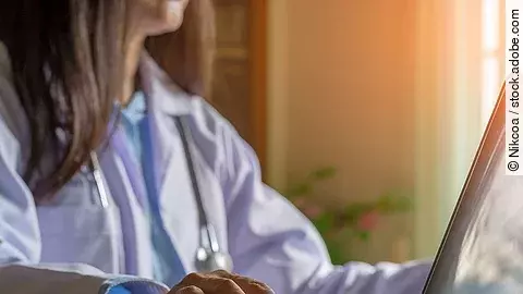 Ärztin am Computer Ärztin sitzt vor dem Computer in weißem Kittel.