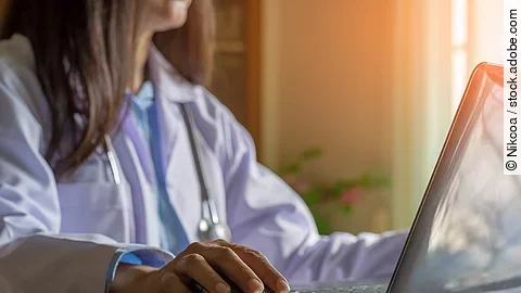 Ärztin am Computer Ärztin sitzt vor dem Computer in weißem Kittel.