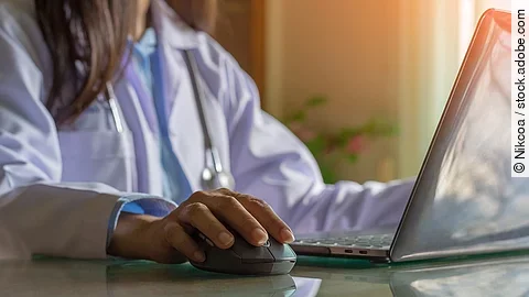 Ärztin am Computer Ärztin sitzt vor dem Computer in weißem Kittel.