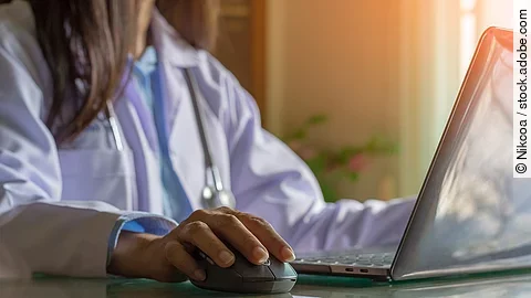 Ärztin am Computer Ärztin sitzt vor dem Computer in weißem Kittel.