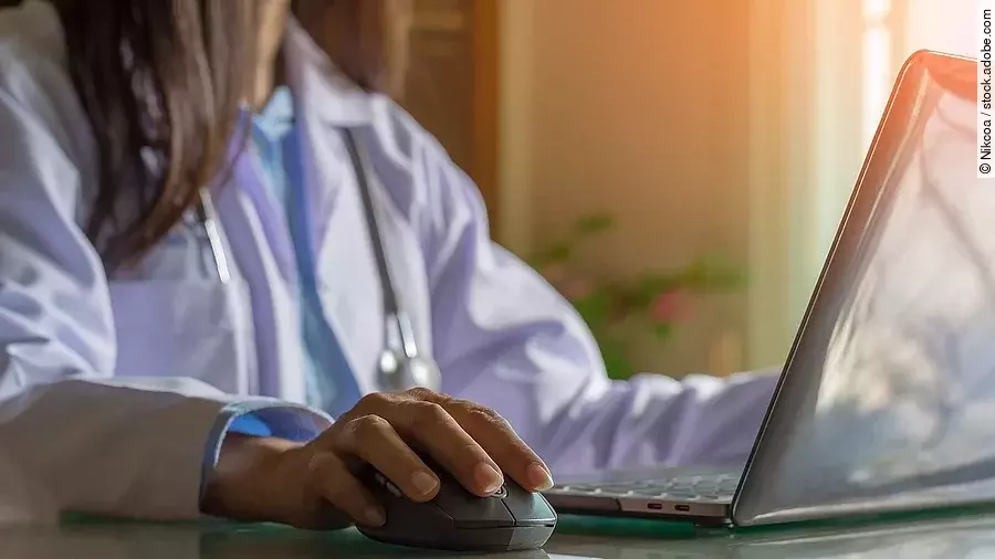 Ärztin sitzt vor dem Computer in weißem Kittel.