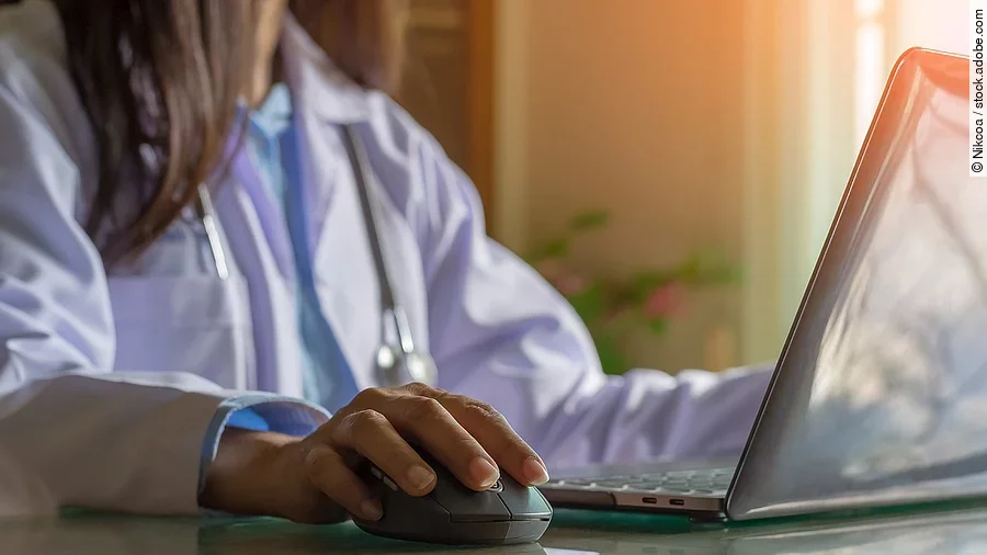 Ärztin am Computer Ärztin sitzt vor dem Computer in weißem Kittel.