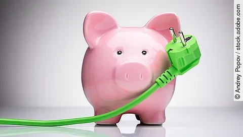 Ein Sparschwein und ein grünes Stromkabel.