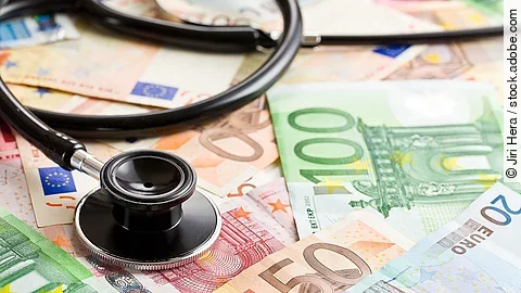 Mehrere Banknoten liegen verteilt und auf ihnen ein Stethoskop.