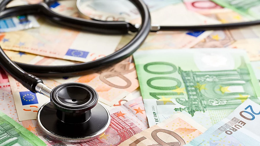Mehrere Banknoten liegen verteilt und auf ihnen ein Stethoskop.