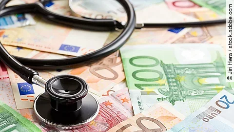 Mehrere Banknoten liegen verteilt und auf ihnen ein Stethoskop.