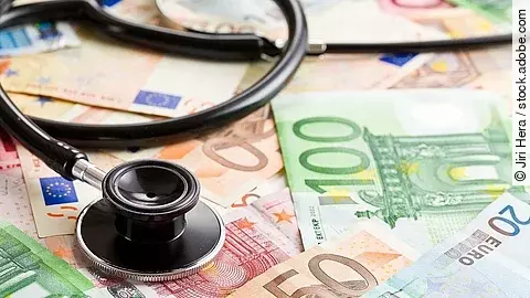 Mehrere Banknoten liegen verteilt und auf ihnen ein Stethoskop.