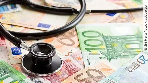 Mehrere Banknoten liegen verteilt und auf ihnen ein Stethoskop.