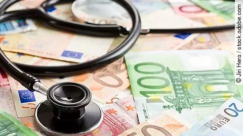 Mehrere Banknoten liegen verteilt und auf ihnen ein Stethoskop.
