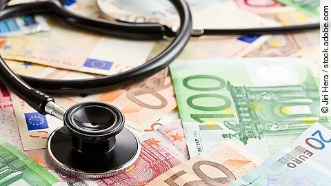 Mehrere Banknoten liegen verteilt und auf ihnen ein Stethoskop.