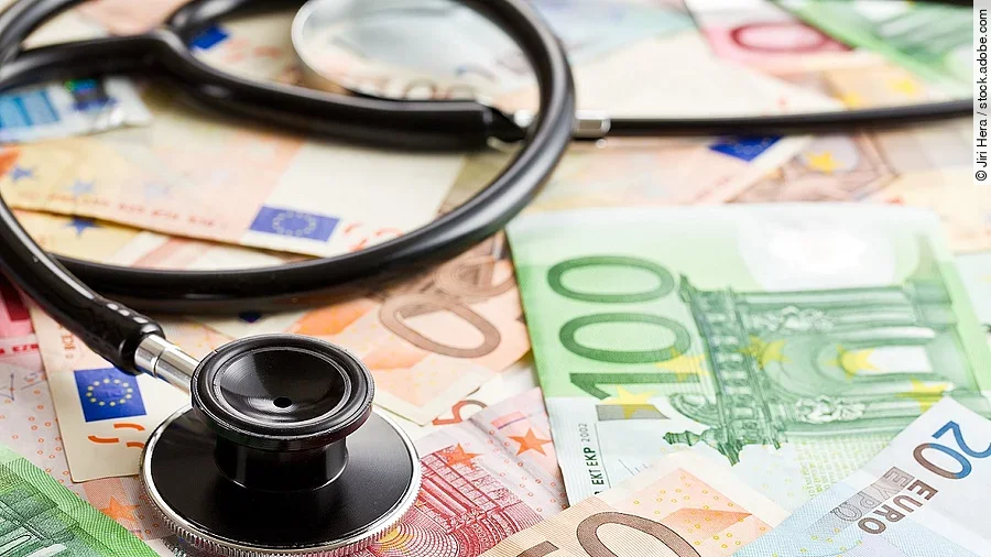 Mehrere Banknoten liegen verteilt und auf ihnen ein Stethoskop.