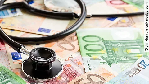 Mehrere Banknoten liegen verteilt und auf ihnen ein Stethoskop.