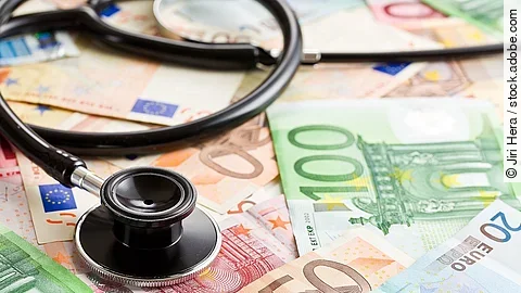 Mehrere Banknoten liegen verteilt und auf ihnen ein Stethoskop.