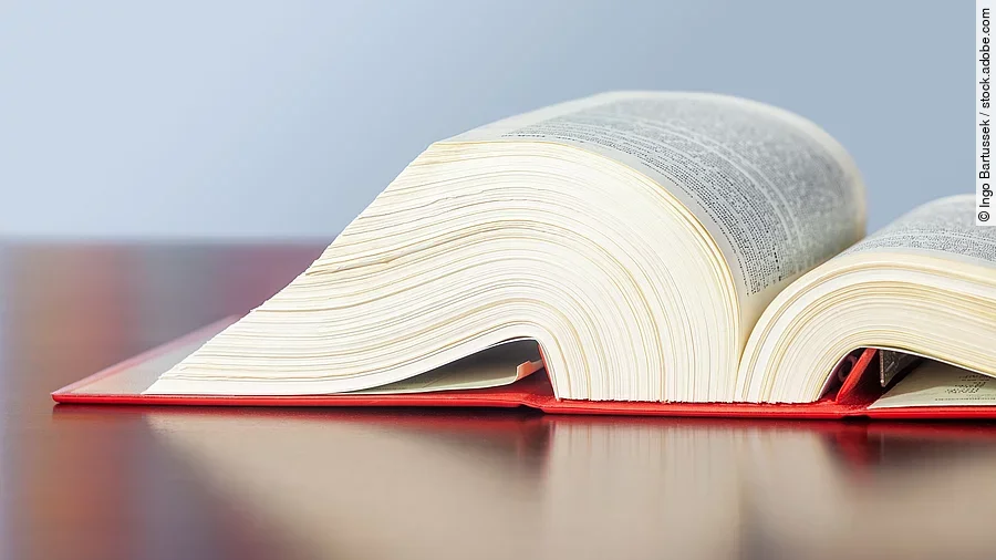 Gesetzbuch liegt aufgeschlagen auf einem Tisch.