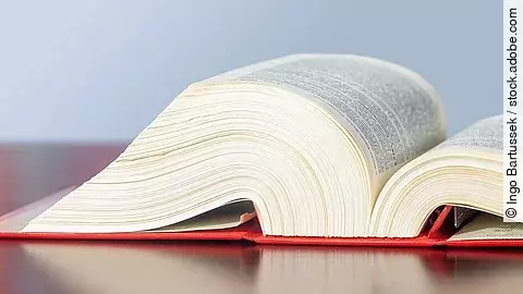 Gesetzbuch liegt aufgeschlagen auf einem Tisch.