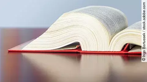 Gesetzbuch liegt aufgeschlagen auf einem Tisch.