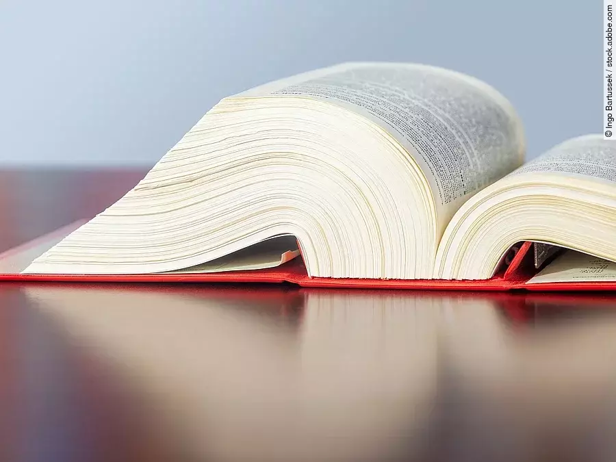 Gesetzbuch liegt aufgeschlagen auf einem Tisch.