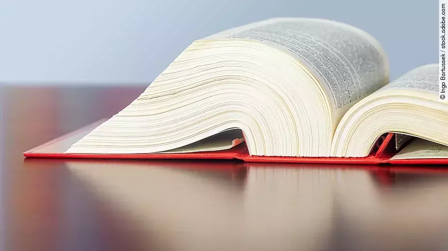 Gesetzbuch liegt aufgeschlagen auf einem Tisch.