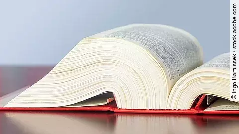 Gesetzbuch liegt aufgeschlagen auf einem Tisch.