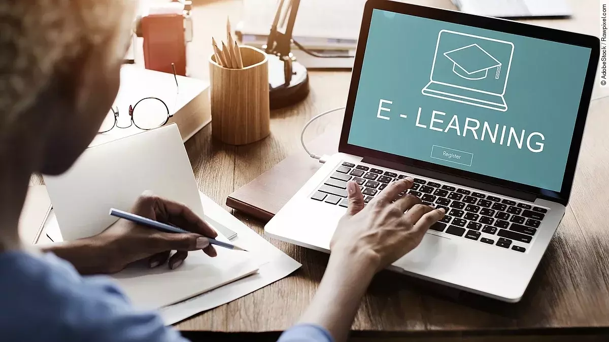 E-Learning Eine Frau sitzt vor einem aufgeklappten Laptop, auf dem Bildschirm steht "E-Learning".