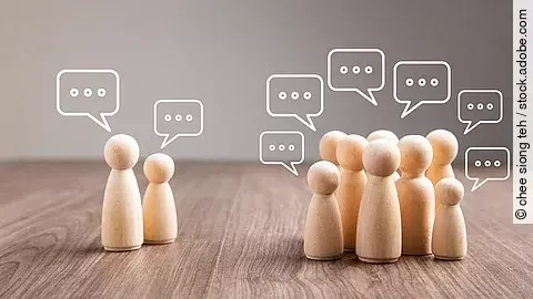 Mehrere Holz-Spielfiguren mit Sprechblasen.