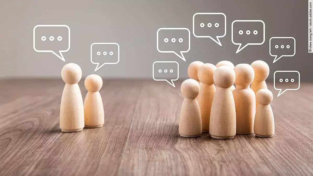 Mehrere Holz-Spielfiguren mit Sprechblasen.