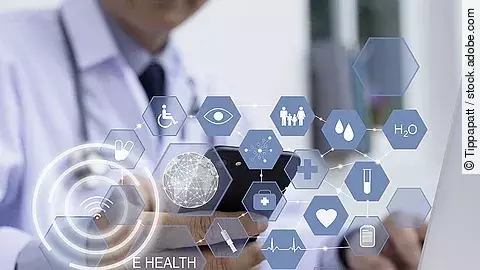 Ein Arzt hält ein Tablet in den Händen. Über dem Gerät schweben Symbole und Icons in einer hologrammartigen Darstellung.