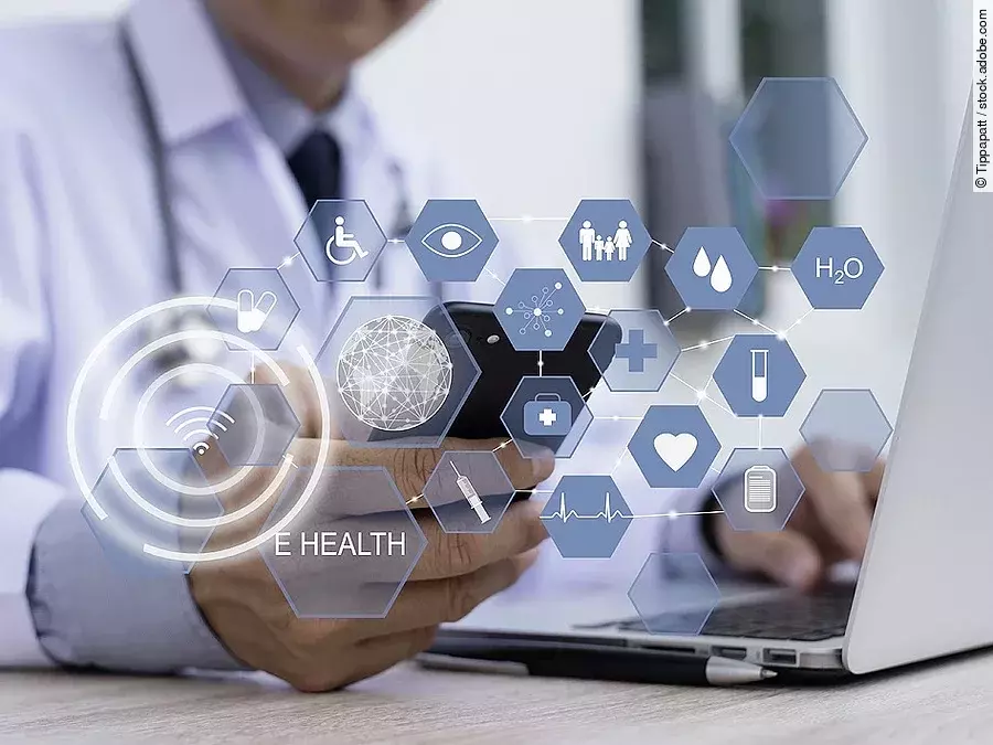 Ein Arzt hält ein Tablet in den Händen. Über dem Gerät schweben Symbole und Icons in einer hologrammartigen Darstellung.