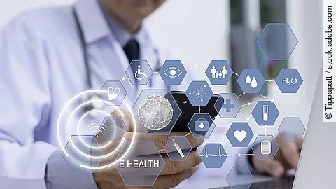 Ein Arzt hält ein Tablet in den Händen. Über dem Gerät schweben Symbole und Icons in einer hologrammartigen Darstellung.