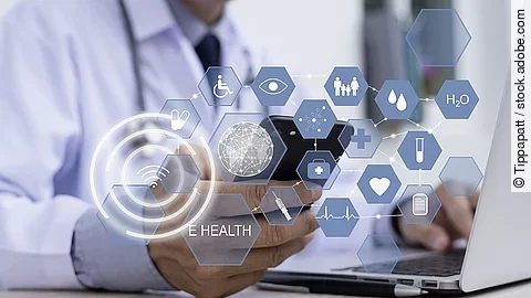 Ein Arzt hält ein Tablet in den Händen. Über dem Gerät schweben Symbole und Icons in einer hologrammartigen Darstellung.