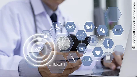 Ein Arzt hält ein Tablet in den Händen. Über dem Gerät schweben Symbole und Icons in einer hologrammartigen Darstellung.