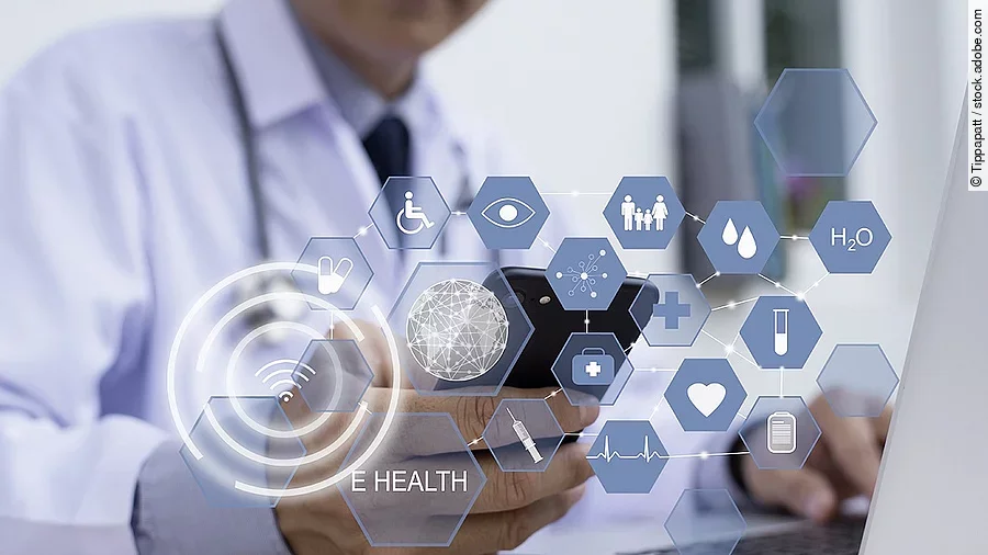 E-Health Ein Arzt hält ein Tablet in den Händen. Über dem Gerät schweben Symbole und Icons in einer hologrammartigen Darstellung.