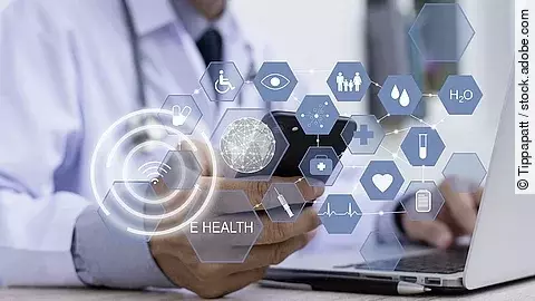 Ein Arzt hält ein Tablet in den Händen. Über dem Gerät schweben Symbole und Icons in einer hologrammartigen Darstellung.