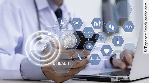 Ein Arzt hält ein Tablet in den Händen. Über dem Gerät schweben Symbole und Icons in einer hologrammartigen Darstellung.