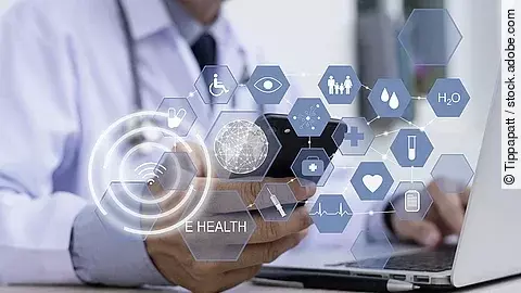 Ein Arzt hält ein Tablet in den Händen. Über dem Gerät schweben Symbole und Icons in einer hologrammartigen Darstellung.