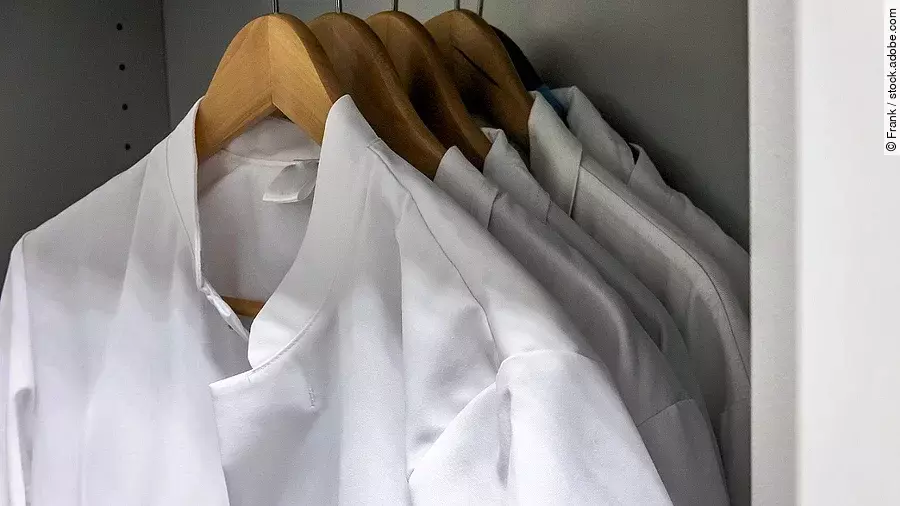 Arztkittel Mehrere Arztkittel hängen auf braunen Kleiderbügeln im Schrank.