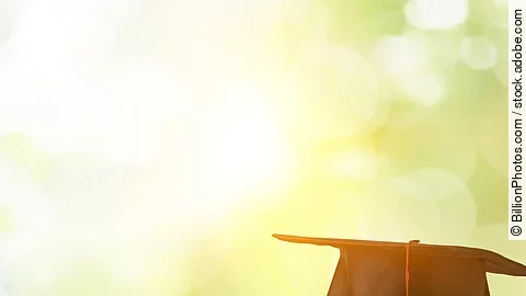 Masterstudium Ein schwarzer Absolventenhut liegt auf zwei Bücherstapeln.