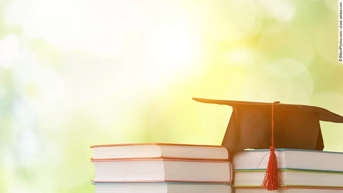 Masterstudium Ein schwarzer Absolventenhut liegt auf zwei Bücherstapeln.