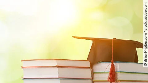 Masterstudium Ein schwarzer Absolventenhut liegt auf zwei Bücherstapeln.