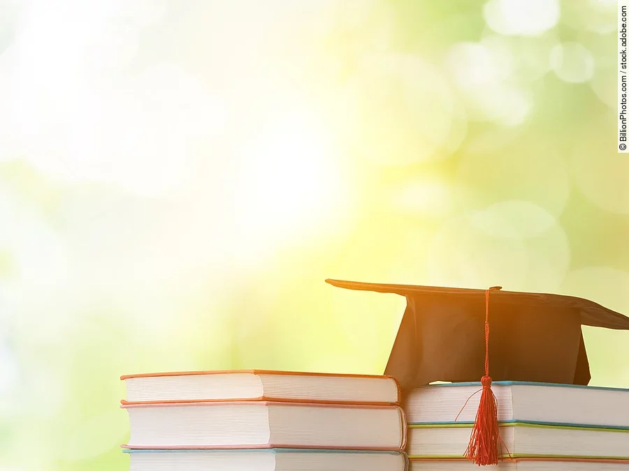 Masterstudium Ein schwarzer Absolventenhut liegt auf zwei Bücherstapeln.