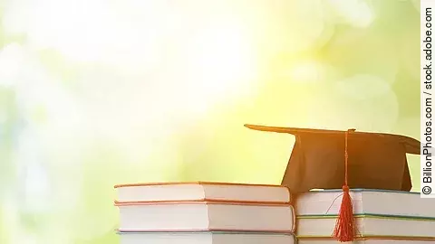 Masterstudium Ein schwarzer Absolventenhut liegt auf zwei Bücherstapeln.