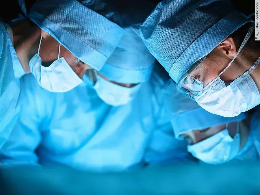 Ärzteteam in OP-Kleidung über einem OP-Tisch geneigt.