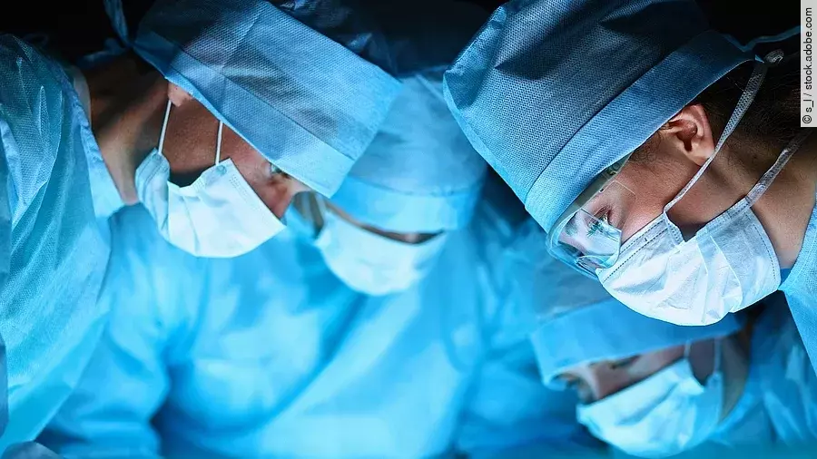 Ärzteteam in OP-Kleidung über einem OP-Tisch geneigt.