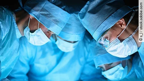 Ärzteteam Ärzteteam in OP-Kleidung über einem OP-Tisch geneigt.
