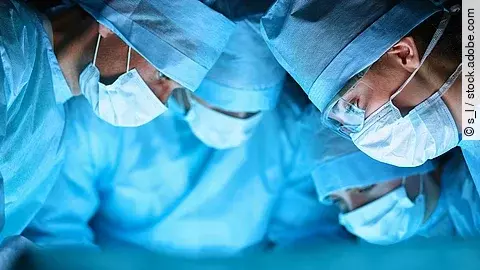 Ärzteteam in OP-Kleidung über einem OP-Tisch geneigt.