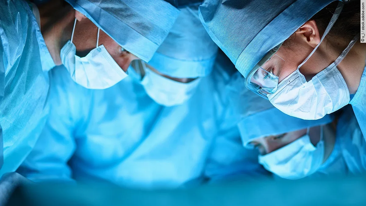 Ärzteteam in OP-Kleidung über einem OP-Tisch geneigt.